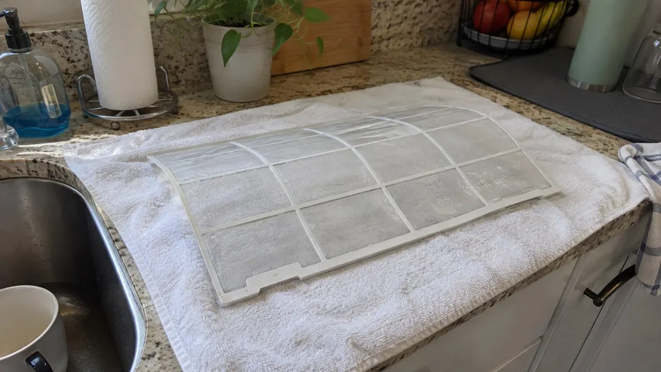 Clean mini split filter drying flat on a white towel on a counter