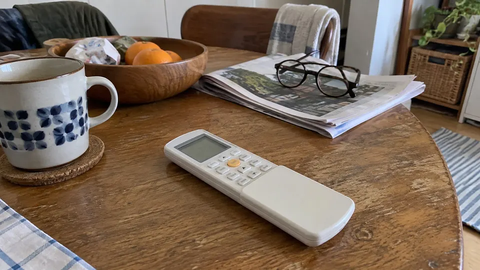 Fujitsu-style sliding-cover remote on an ordinary household table