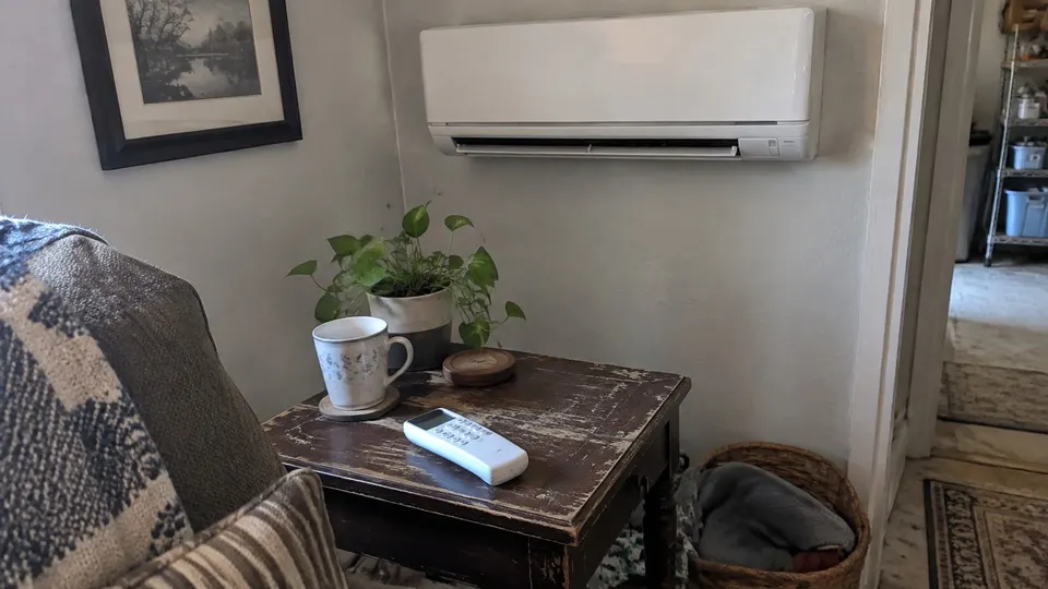 LG-style remote on a worn side table beside a wall mini split