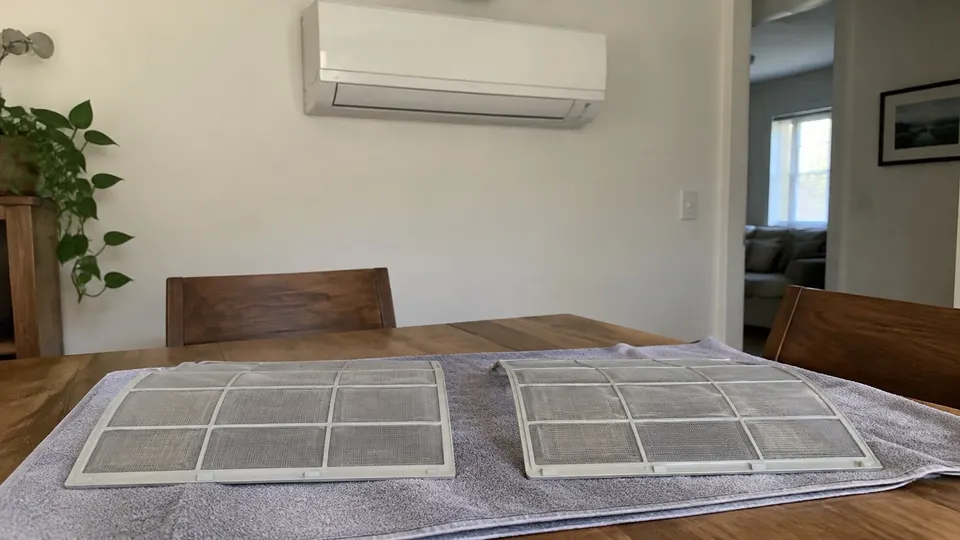 Two mesh mini split filters on a household towel with a closed unit behind them