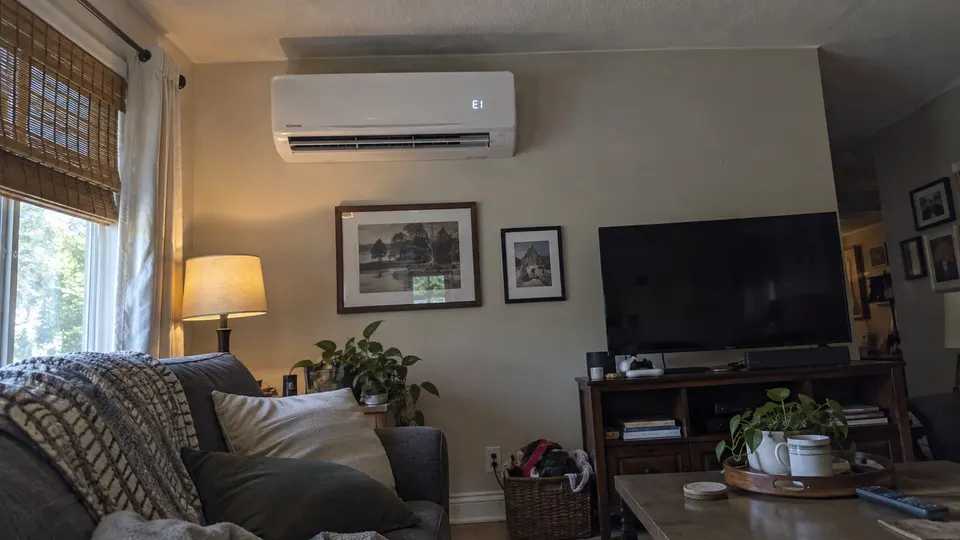 Wall mounted mini split indoor unit with a small error code showing on its display in a living room